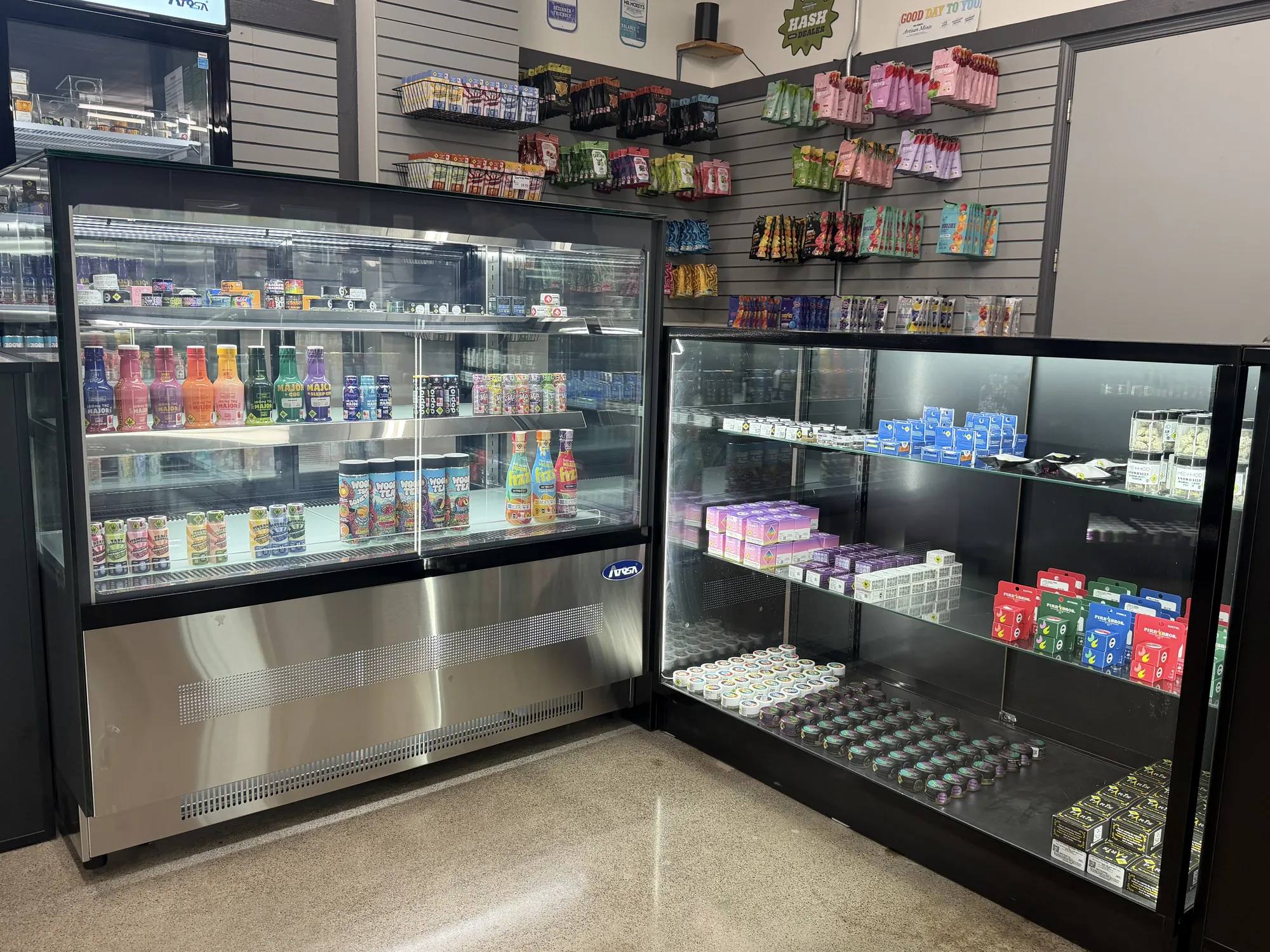 A refrigerated drink display beside a lit glass case at Crystal Leaves