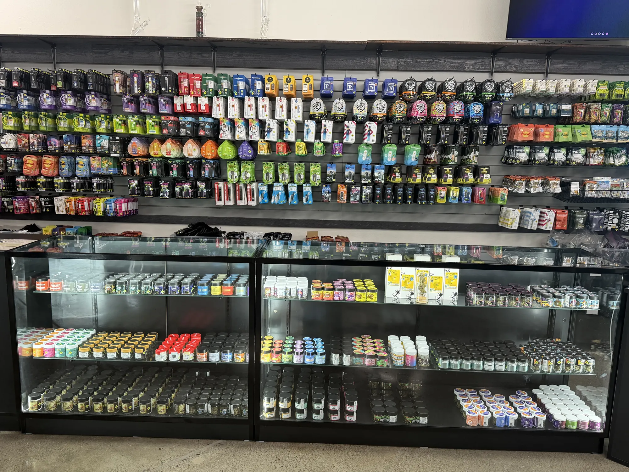 A long wall of cannabis products above lit glass display cases at Crystal Leaves